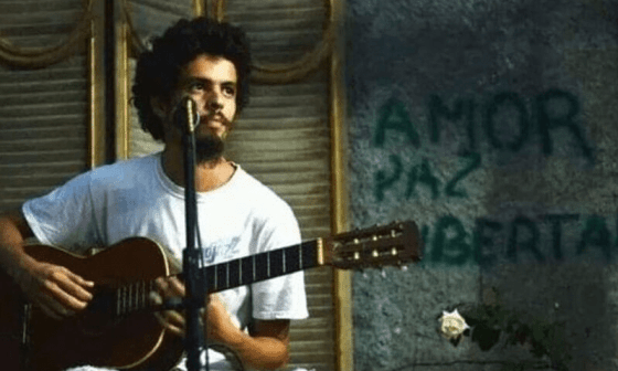 Joven sentado tocando la guitarra. 